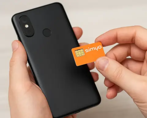 Mano insertando una tarjeta SIM de Simyo en un smartphone negro, representando el proceso de activación o cambio de tarifa móvil con la operadora.